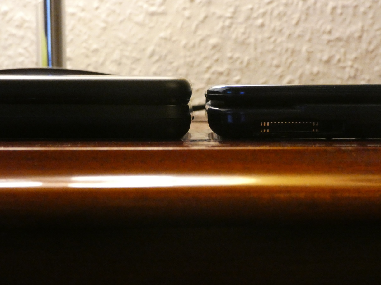 A photo of two devices (the keyboard case and the New Nintendo 3DS XL) next to each other on a table, this time photographed from the side and at level with the table so the thickness or height can be compared. The keyboard case is a little higher.