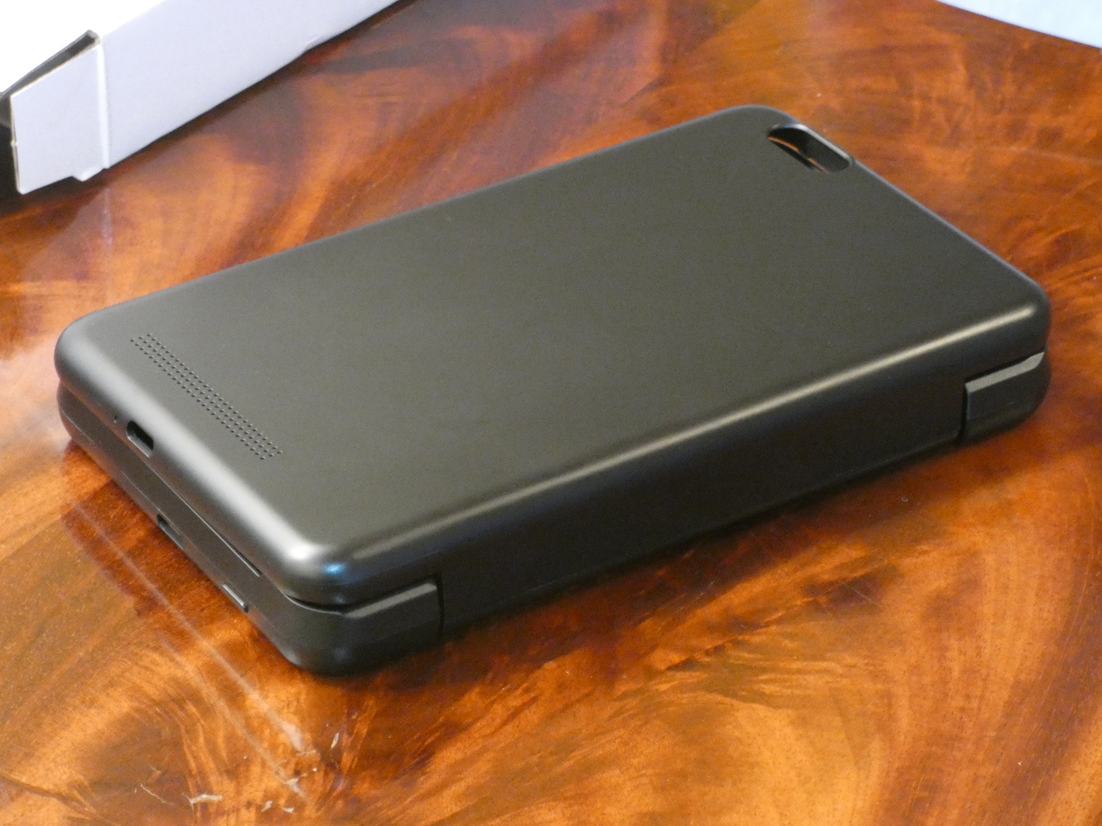A photo of the empty closed keyboard case in a three-quarter perspective with the camera hole corner in the back and the USB ports and battery button on the short side being visible.