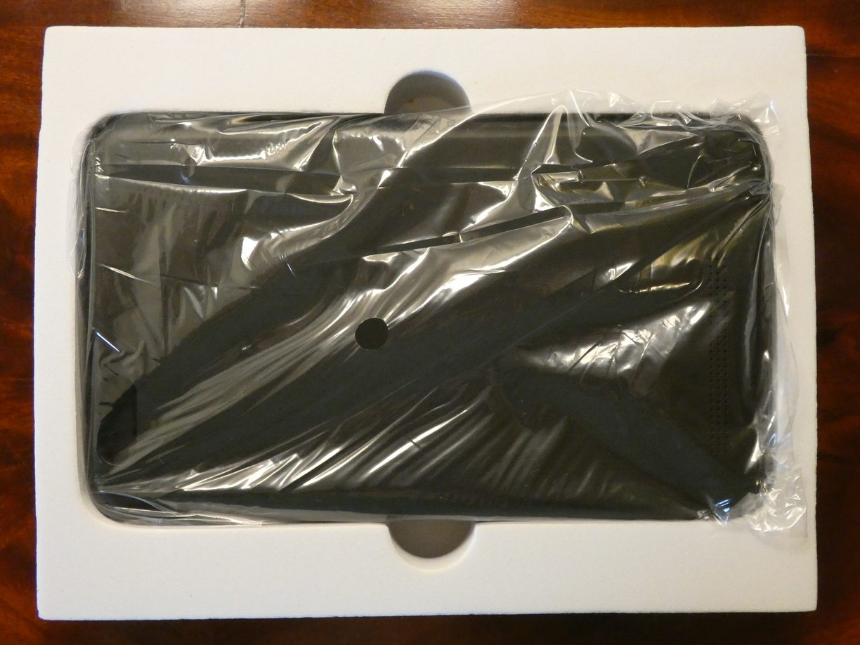 A photo of the opened flat white box with the keyboard case inside, wrapped in a layer of transparent plastic.
